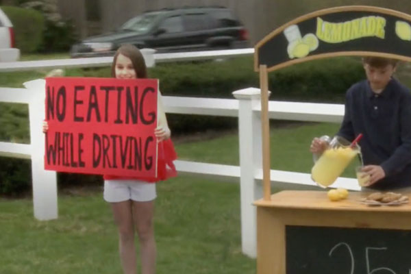 girl holding sign that says no eating while driving