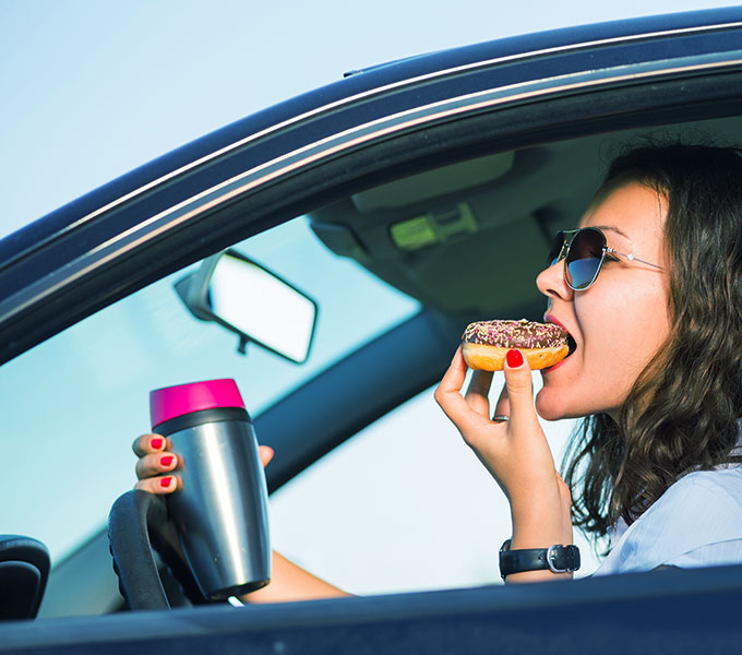 women eating and holding a water bottle while driving