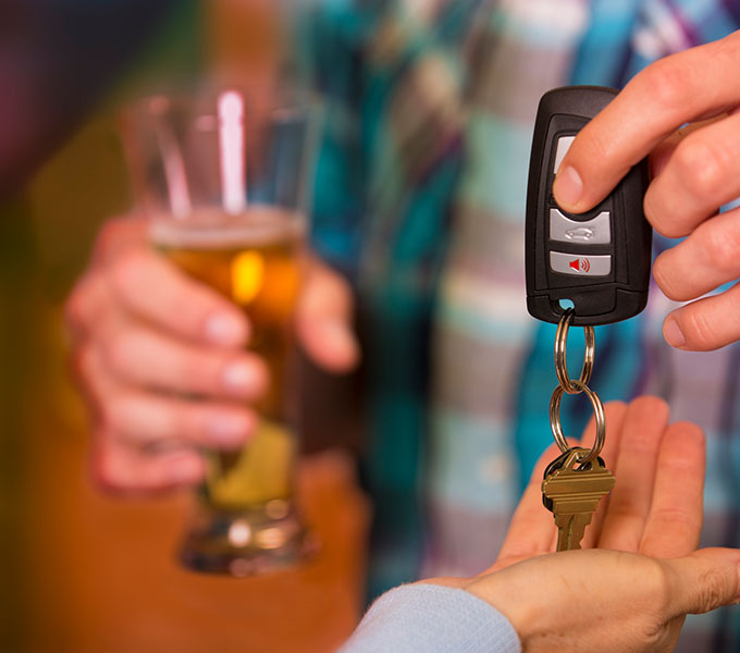 man drinking and handing over his car keys