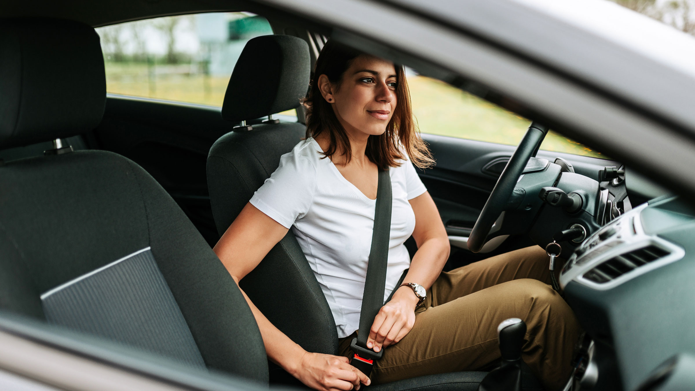 mixed race women putting on her seatbelt in a car