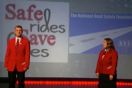 Two FCCLA representatives on a stage with the safe rides save lives logo