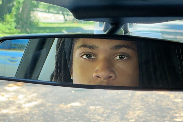 teens face in a rear view mirror