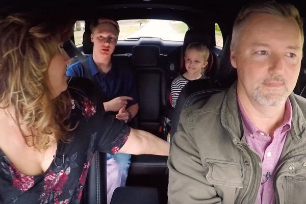 family inside a car, parents in the front seats and kids in the back