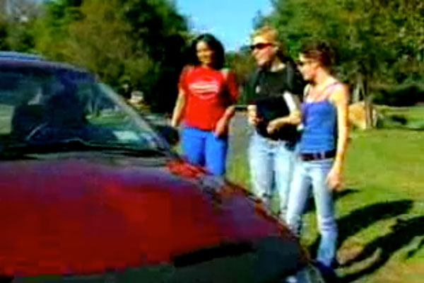 3 women standing next to a red sports car